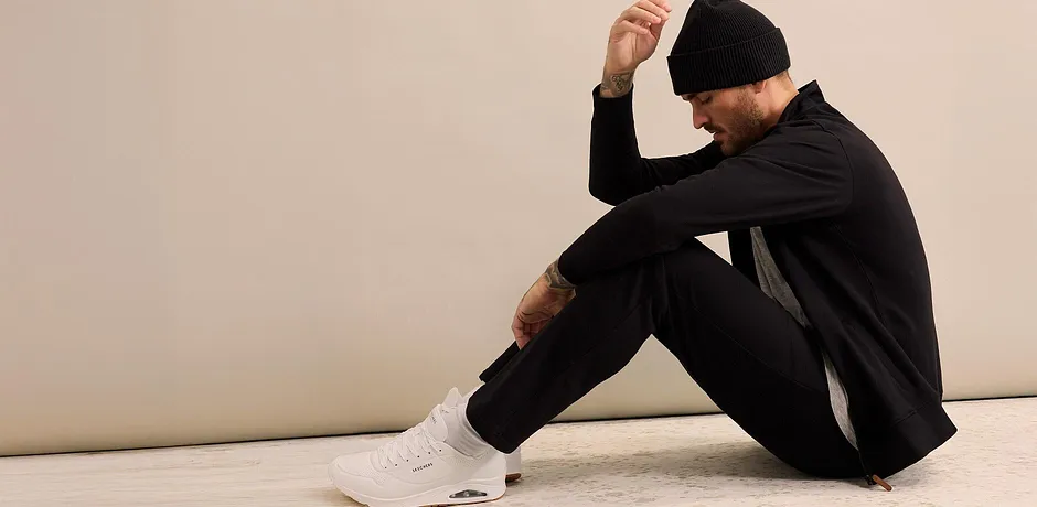 Svart joggingoverall med mössa och vita sneakers.

