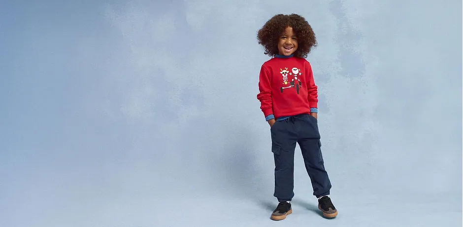 Röd tröja med julmotiv, blå jeans och bruna skor.

