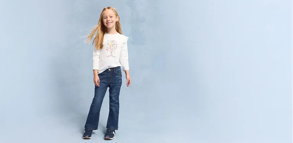 Ledig look med vit långärmad tröja och utsvängda jeans.

