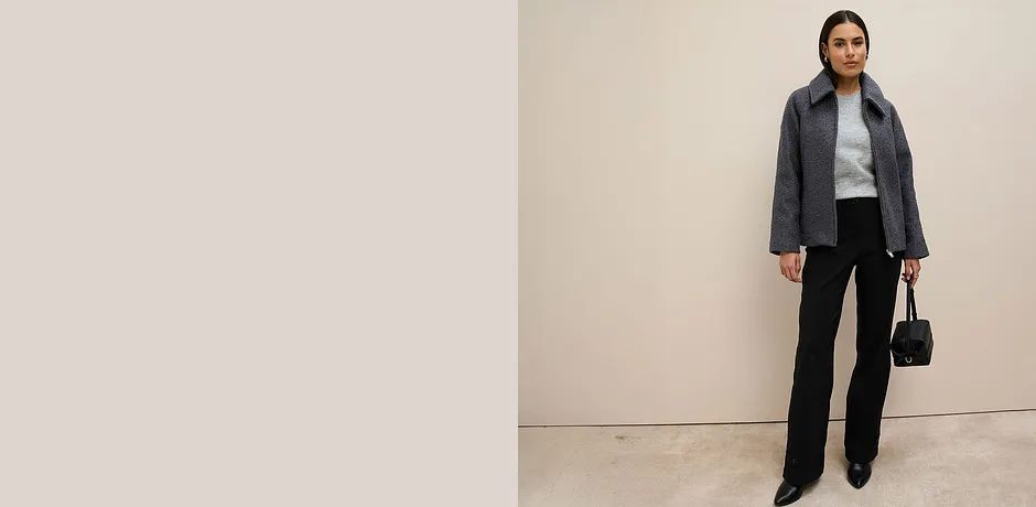 Grå jacka, grå tröja och svarta byxor.

