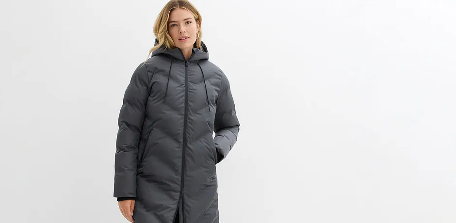 Lång, grå vinterkappa med huva och dragkedja.

