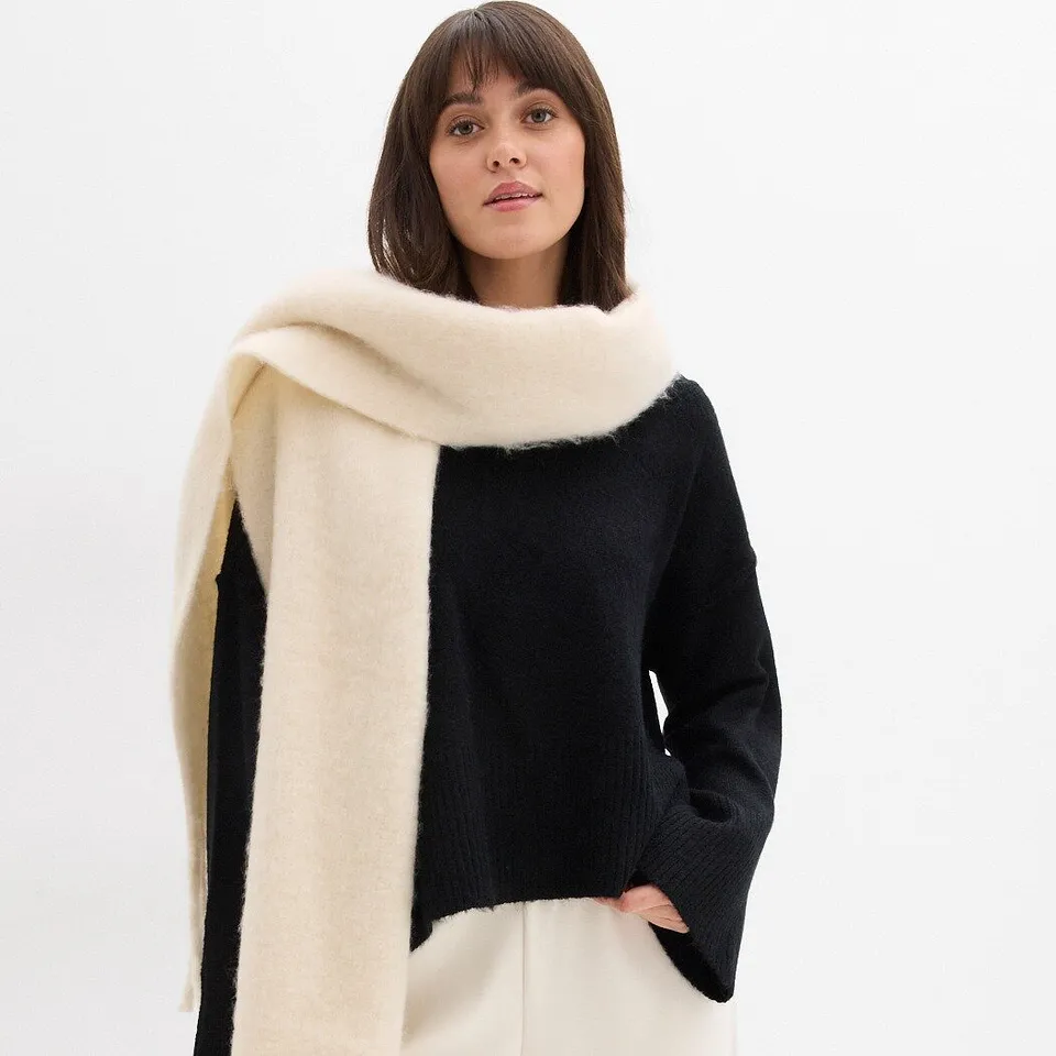 Svart tröja kombinerad med cremefärgad halsduk.

