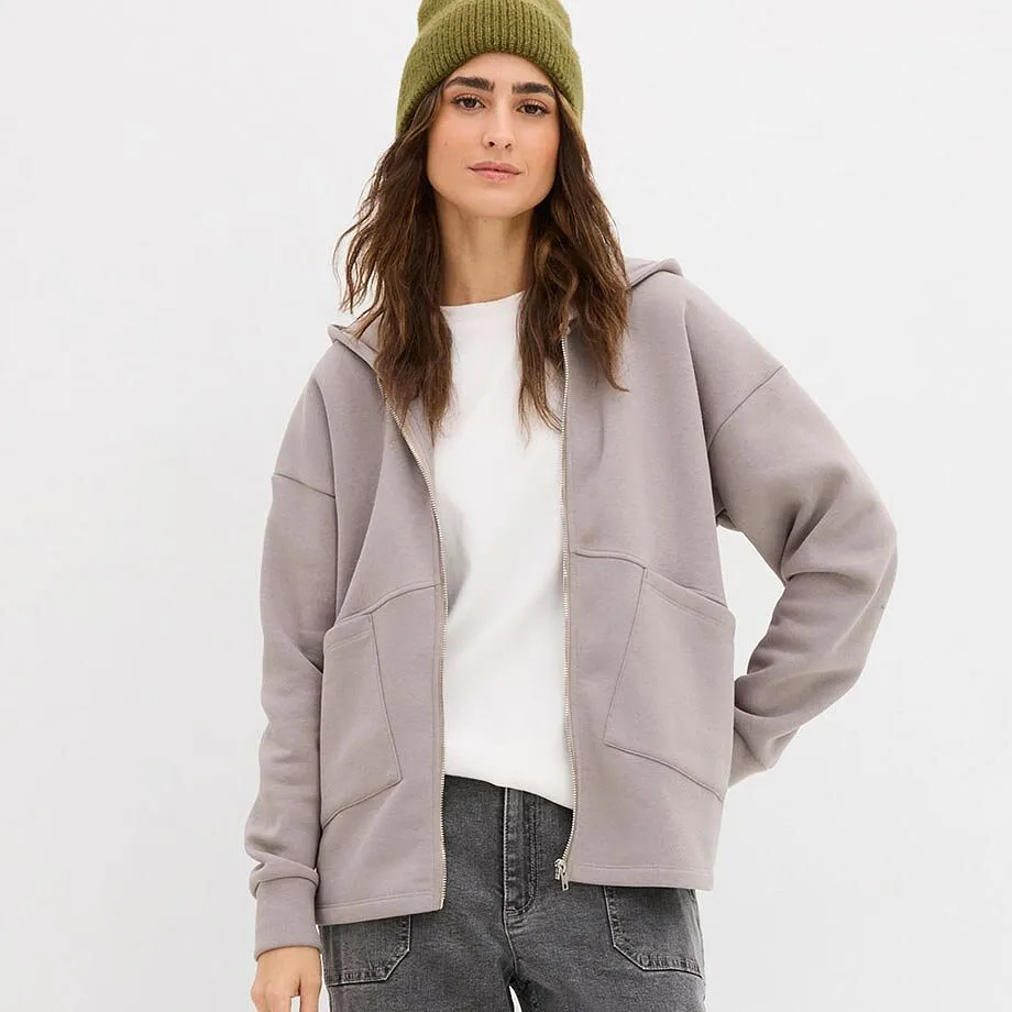 Vit tröja och grå sweatjacka över grå jeans.

