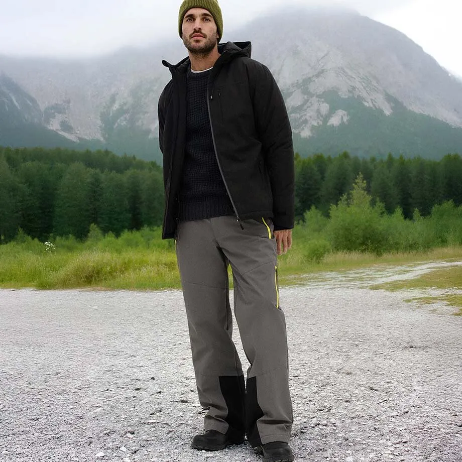 M&ouml;rk vinterjacka, gr&aring; byxor och en gr&ouml;n m&ouml;ssa.