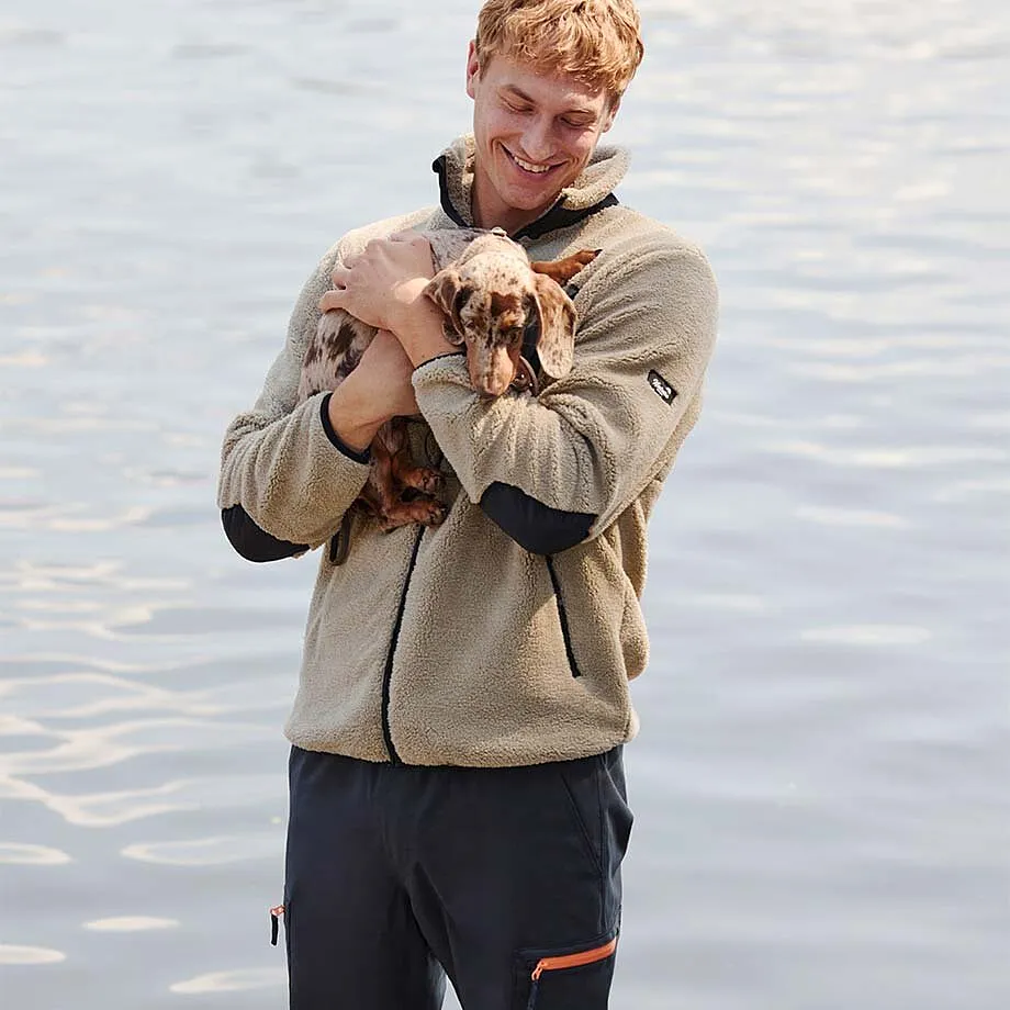 Beige fleecejacka kombinerad med m&ouml;rka byxor.