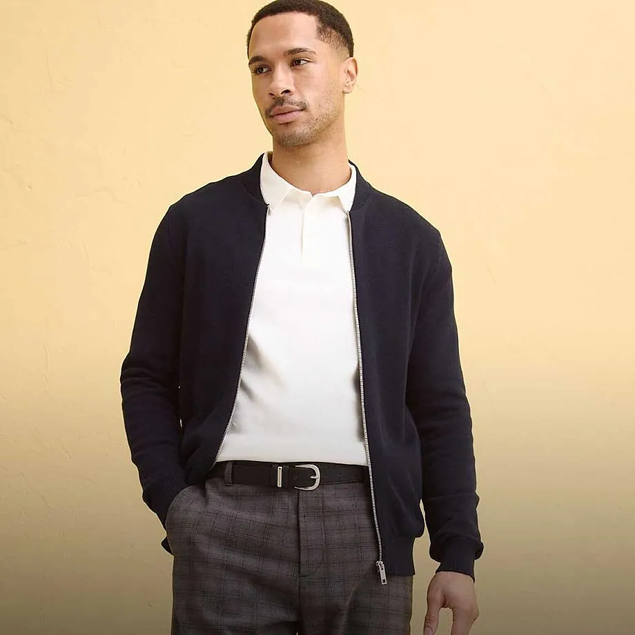 M&ouml;rk cardigan &ouml;ver vit pik&eacute;tr&ouml;ja, kombinerat med gr&aring; byxor.

