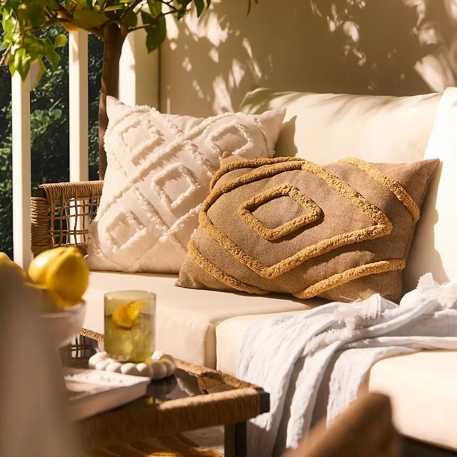 Mysig utomhuslounge med ljusa kuddar och mjuk filt.

