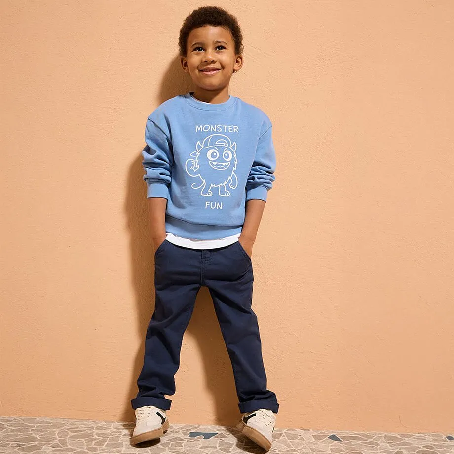 Ljusbl&aring; tr&ouml;ja med vitt tryck, m&ouml;rka jeans och beige skor f&ouml;r en ledig outfit.