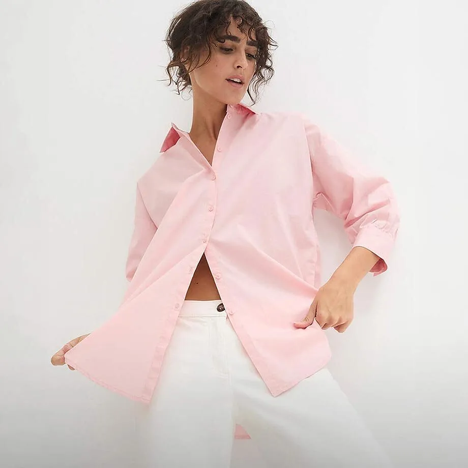 Ljusrosa skjortblus med l&aring;nga &auml;rmar &ouml;ver vita byxor.