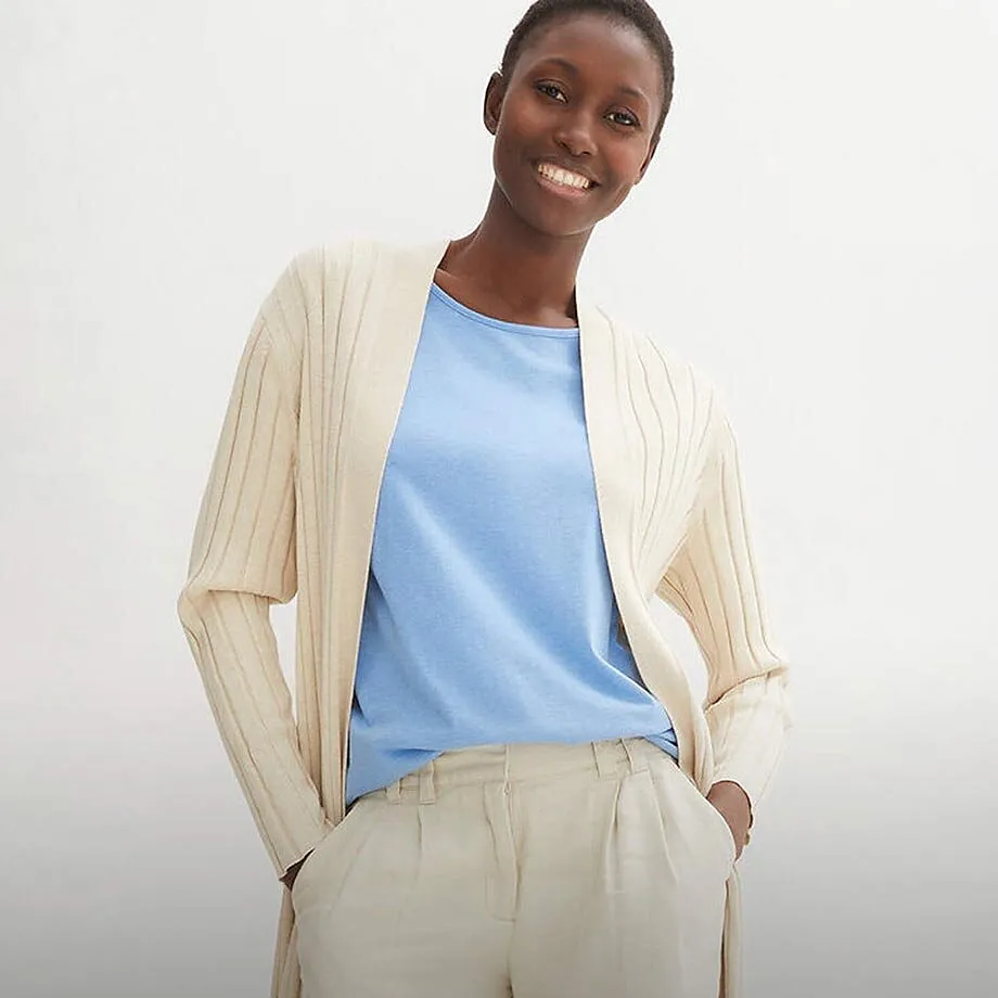 Cremef&auml;rgad cardigan &ouml;ver en ljusbl&aring; topp, kombinerad med ljusa kostymbyxor.