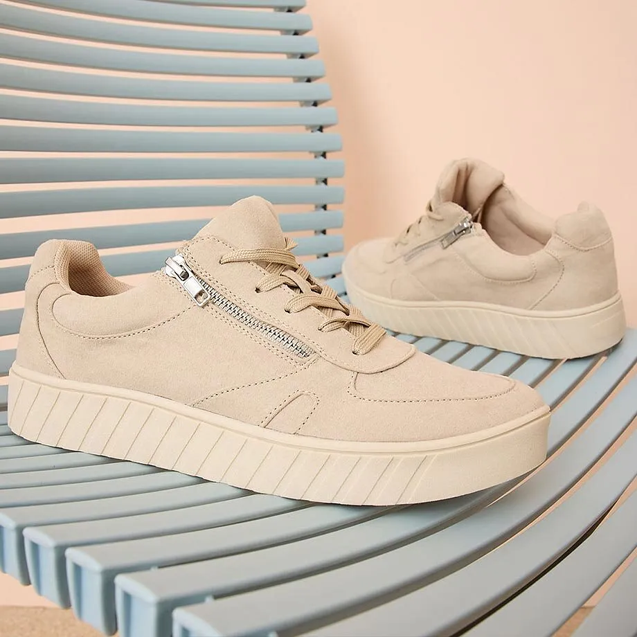 Beige sneakers med dragkedja och sula med struktur.