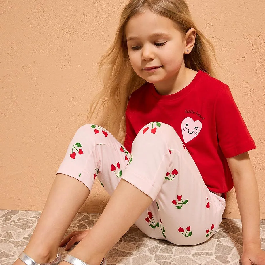 En liten flicka b&auml;r en r&ouml;d T-shirt med hj&auml;rtmotiv.