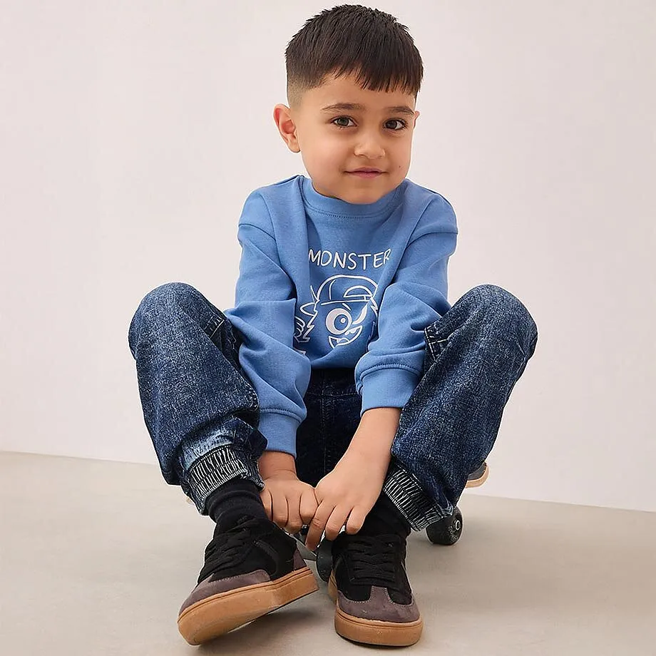 En liten pojke sitter p&aring; golvet.