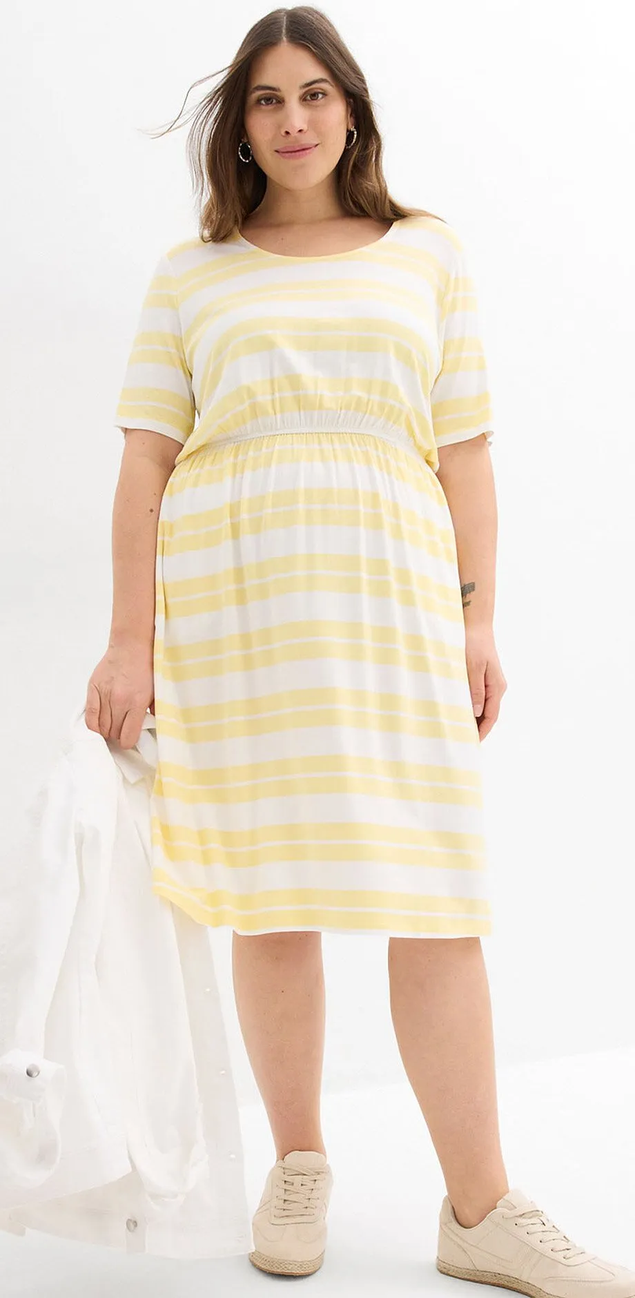 Ljusgulrandig kl&auml;nning och beiga sneakers.

