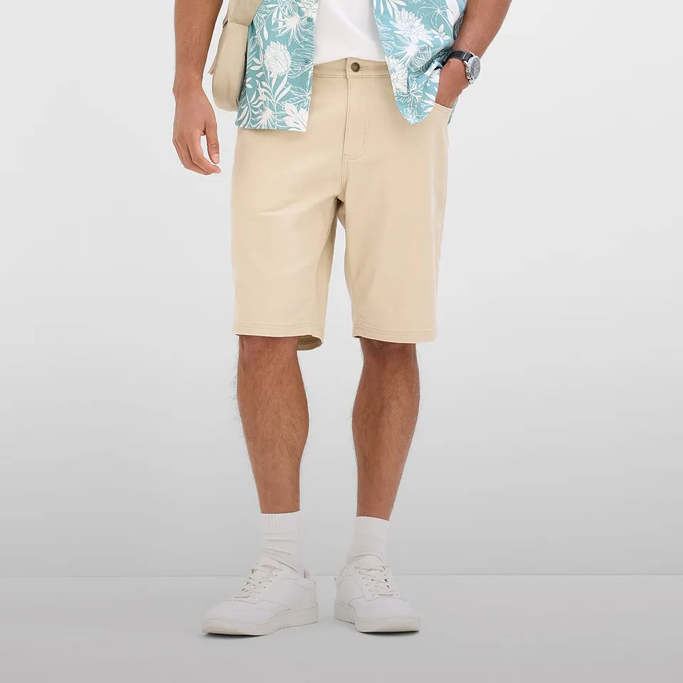 Ledig sommaroutfit med beiga bermudashorts, m&ouml;nstrad skjorta och vita sneakers.

