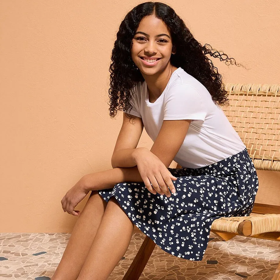 Vit t-shirt och en m&ouml;rkbl&aring; kjol med vitt blomm&ouml;nster.

