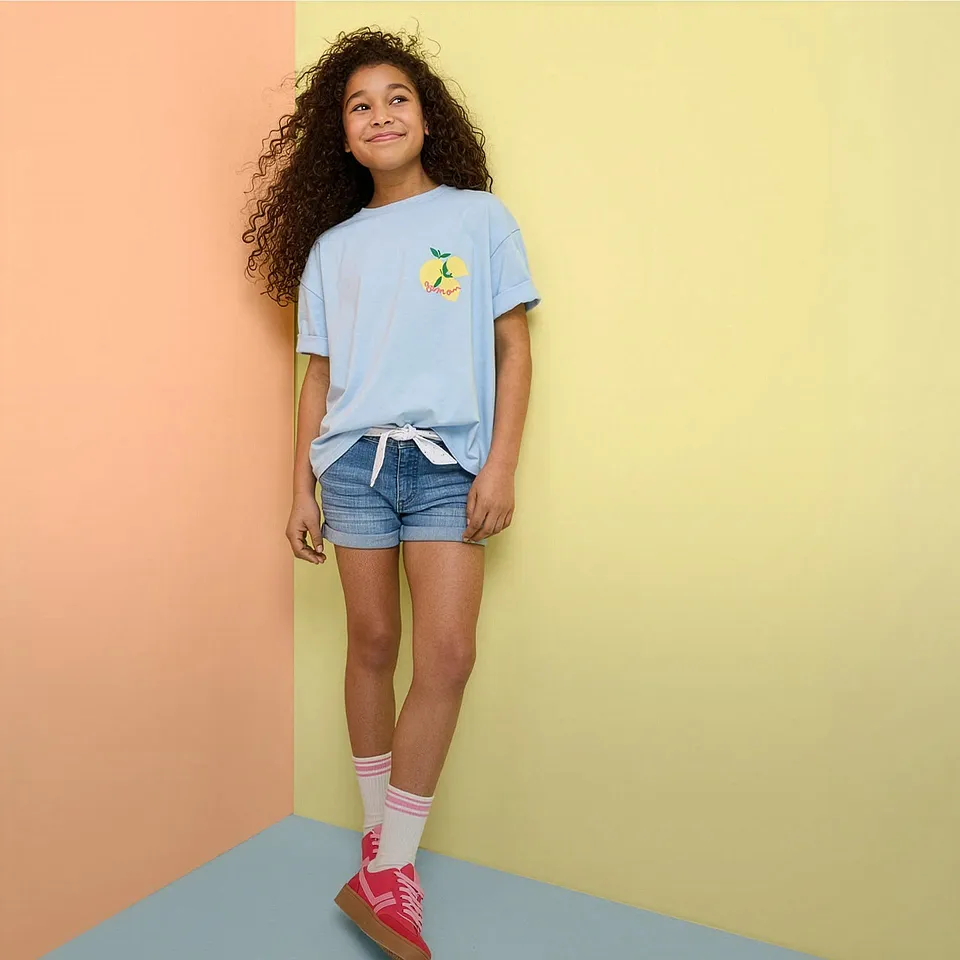 Sommaroutfit med ljusbl&aring; t-shirt, jeansshorts och f&auml;rgglada sneakers.

