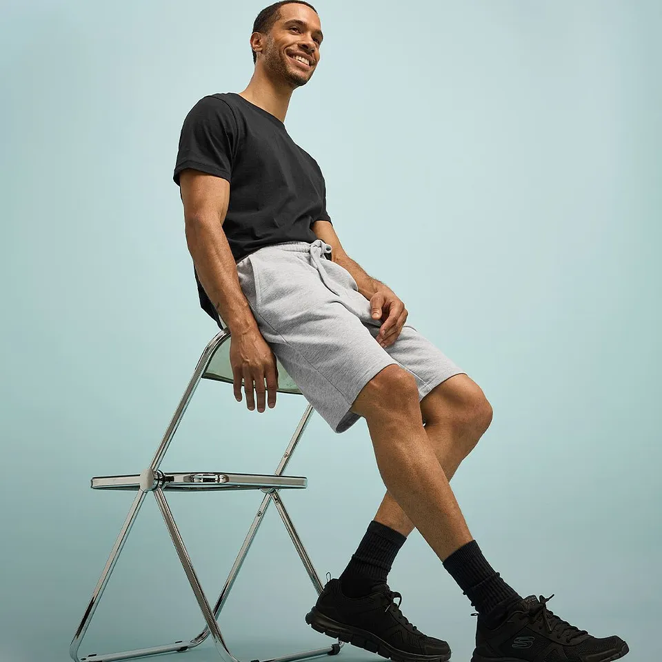 En avslappnad look med en svart T-shirt, ljusa shorts och m&ouml;rka sneakers med strumpor.

