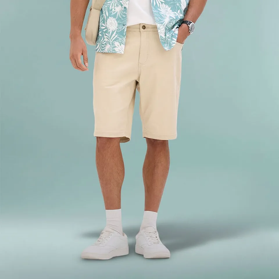 Ledig sommaroutfit med beiga bermudashorts, m&ouml;nstrad skjorta och vita sneakers.

