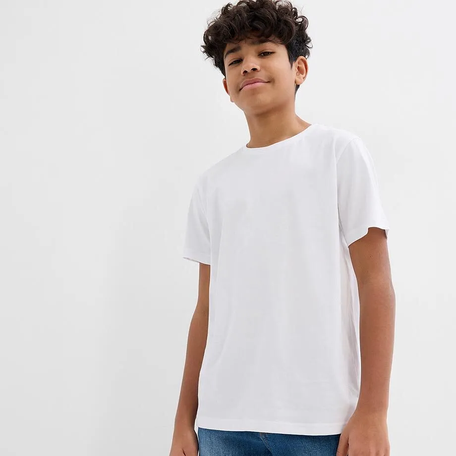 En pojke b&auml;r en vit T-shirt och bl&aring; jeans.