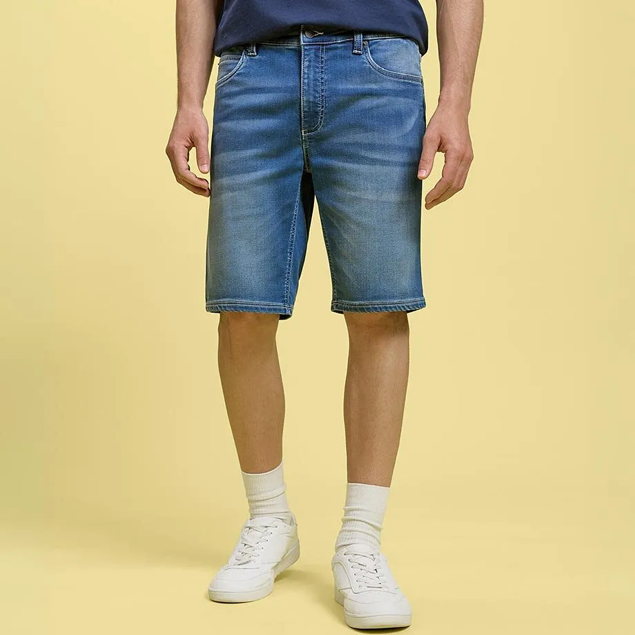 Avslappnade jeansshorts och bl&aring; T-shirt kombinerat med vita sneakers och strumpor.

