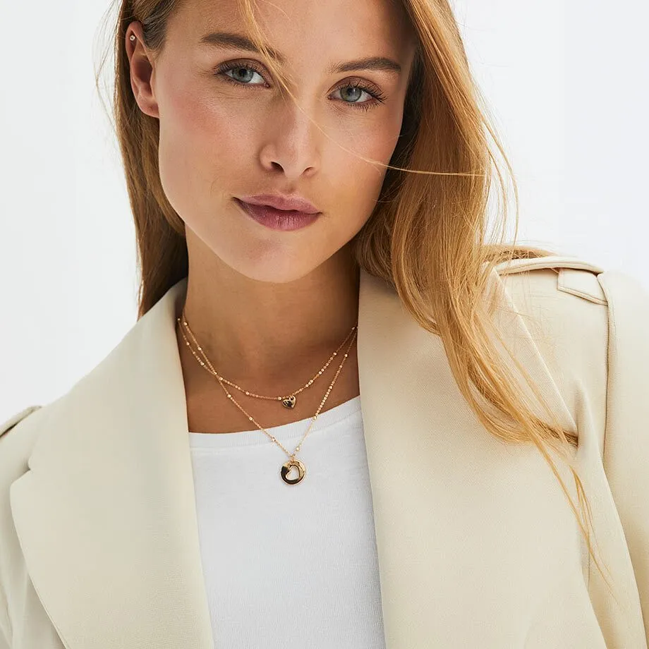 Kvinnan b&auml;r en ljusbeige kavaj tillsammans med ett halsband.