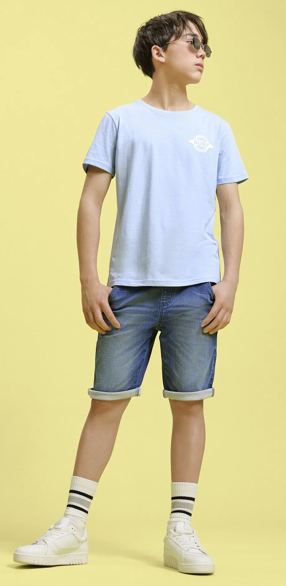 Ljusbl&aring; t-shirt och jeansshorts.

