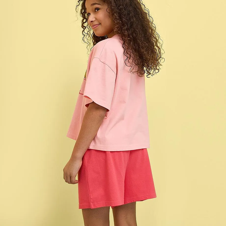 L&ouml;st sittande rosa T-shirt och bekv&auml;ma r&ouml;da shorts.

