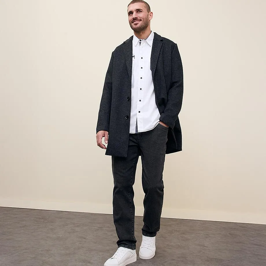 En m&ouml;rk rock &ouml;ver en vit skjorta, matchande jeans och vita sneakers.

