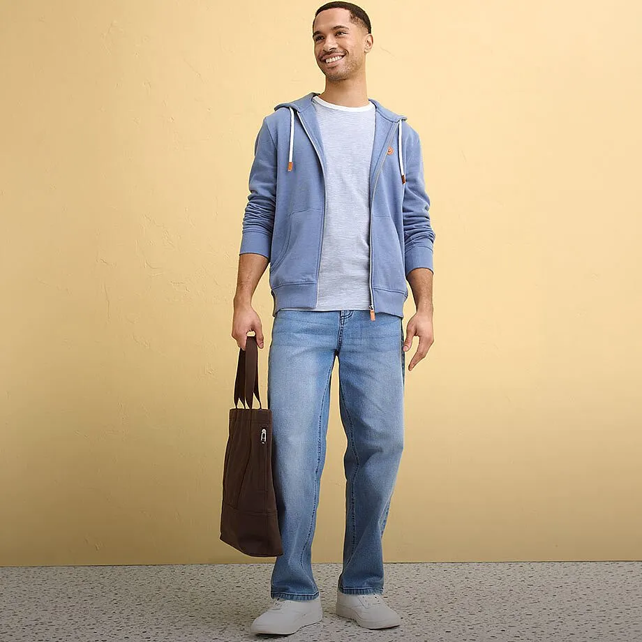 Bl&aring; huvtr&ouml;ja, ljus T-shirt, jeans och vita sneakers f&ouml;r en avslappnad stil.
