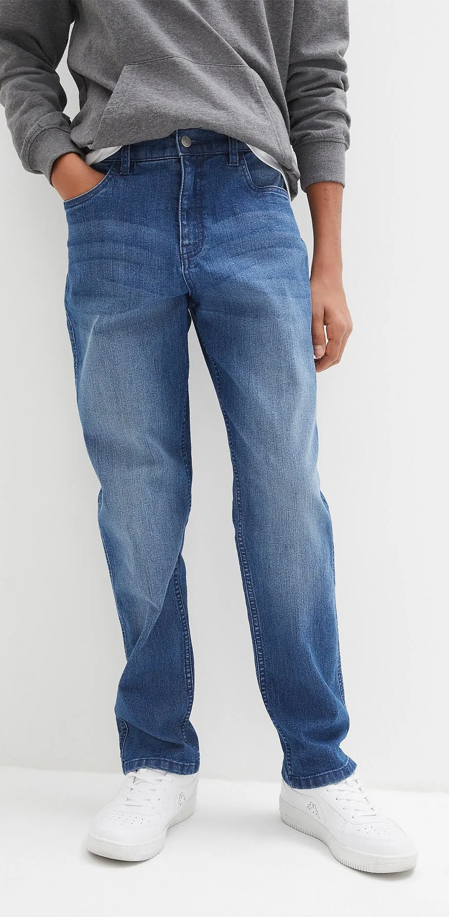 Gr&aring; hoodie, bl&aring; jeans och vita sneakers skapar en avslappnad outfit.