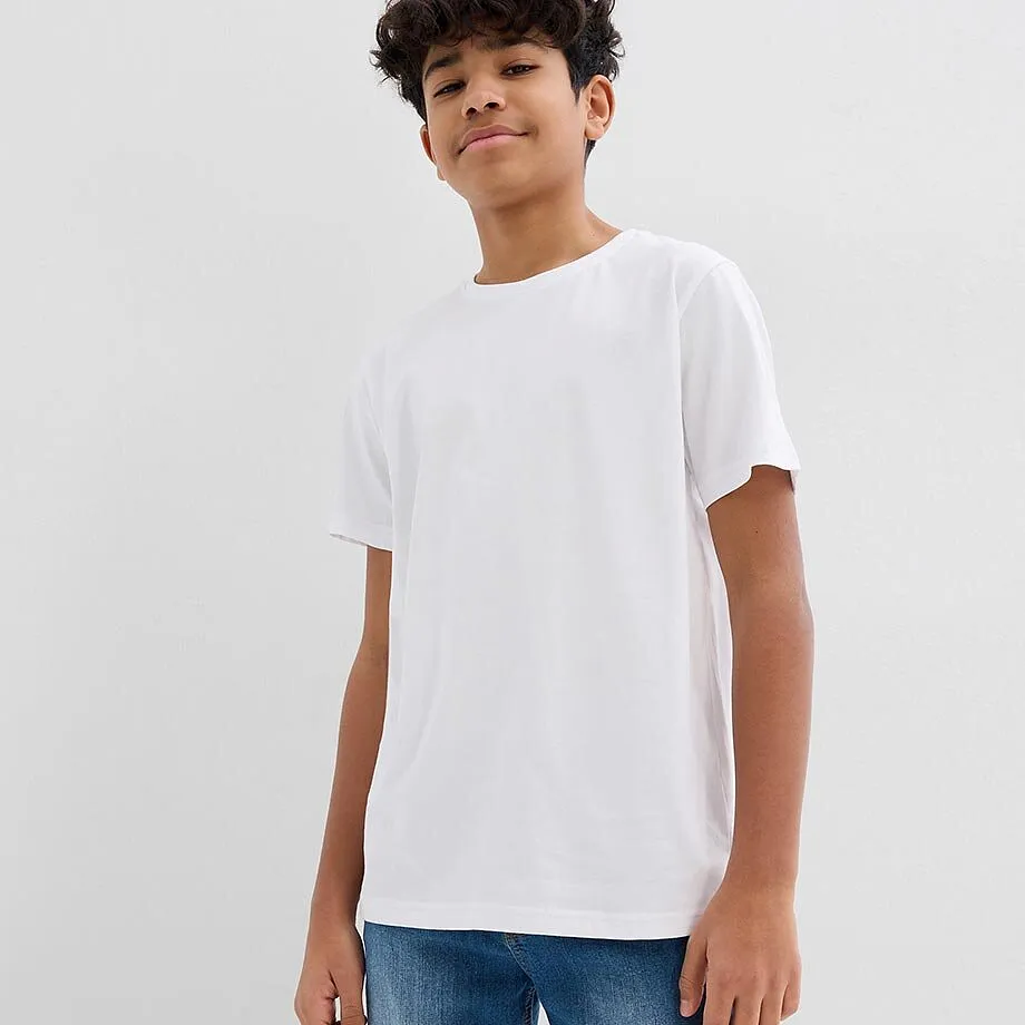Pojken b&auml;r en enkel vit T-shirt och bekv&auml;ma bl&aring; jeans.