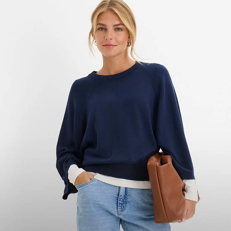 M&ouml;rkbl&aring; tr&ouml;ja, ljusa jeans och en brun handv&auml;ska.