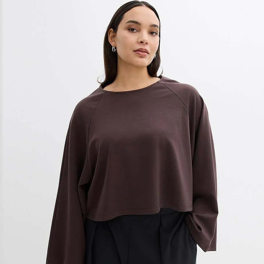 M&ouml;rkbl&aring;, l&aring;ng&auml;rmad topp med vida &auml;rmar och en elegant, svart byxa.