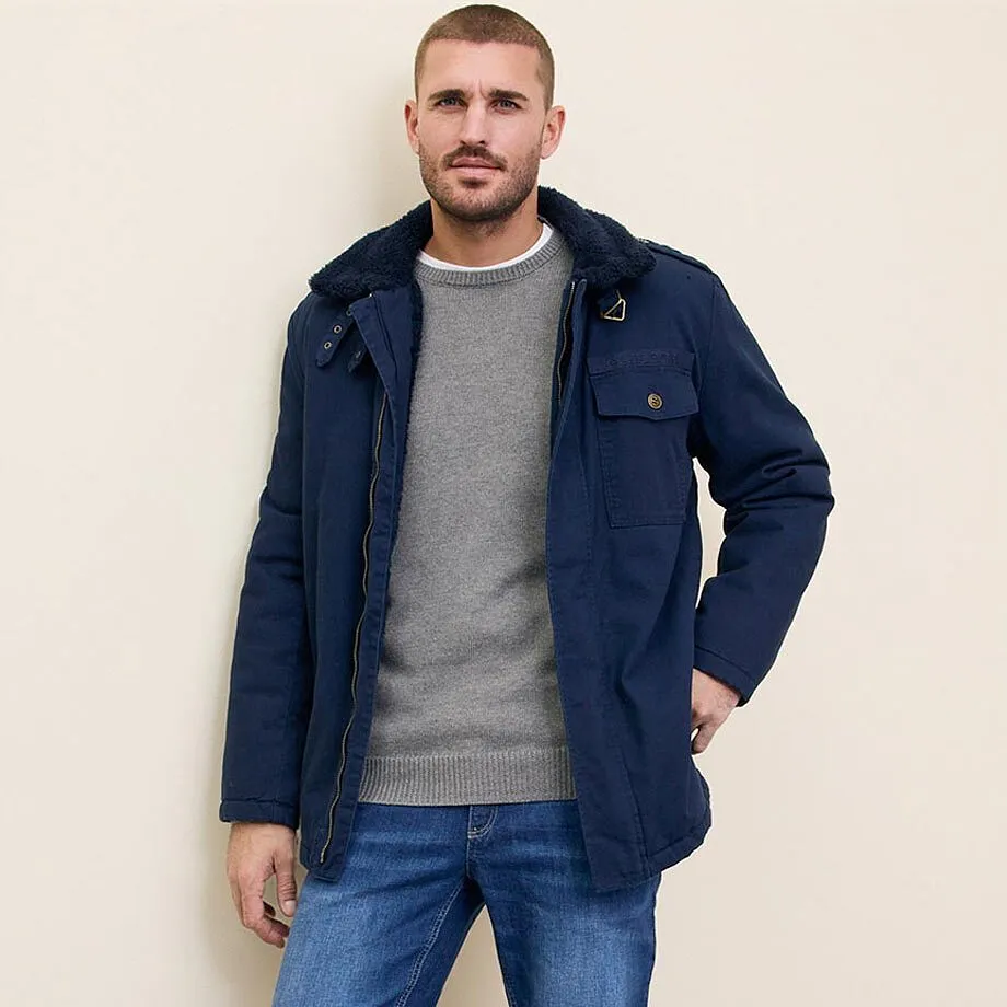 Bl&aring; jacka, gr&aring; tr&ouml;ja och jeans.

