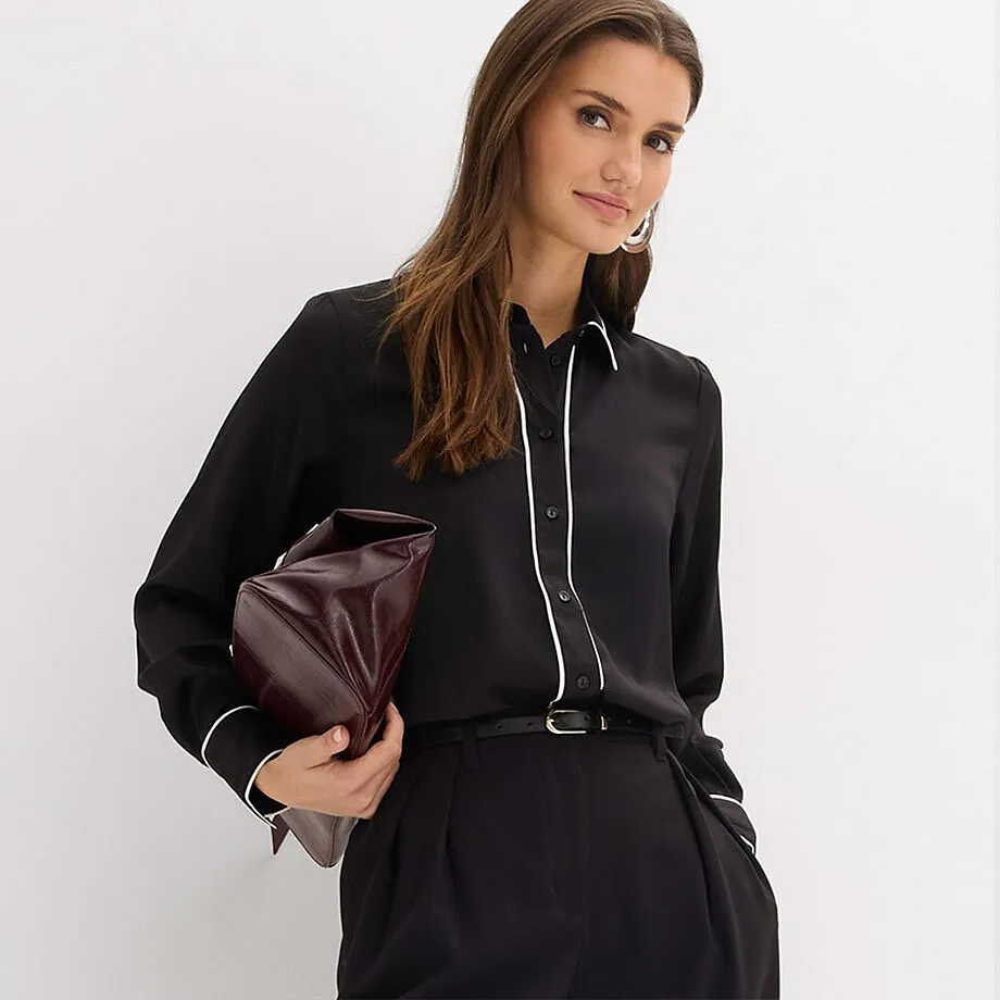 Svart skjortblus med vit krage, kombinerat med svarta byxor.

