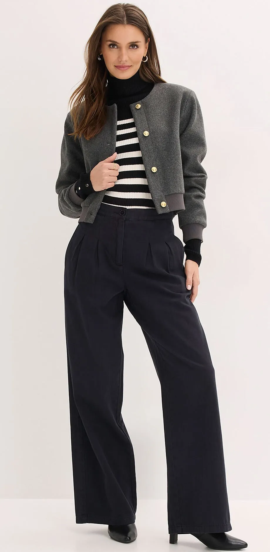 Gr&aring; jacka, randig tr&ouml;ja och vida svarta byxor.

