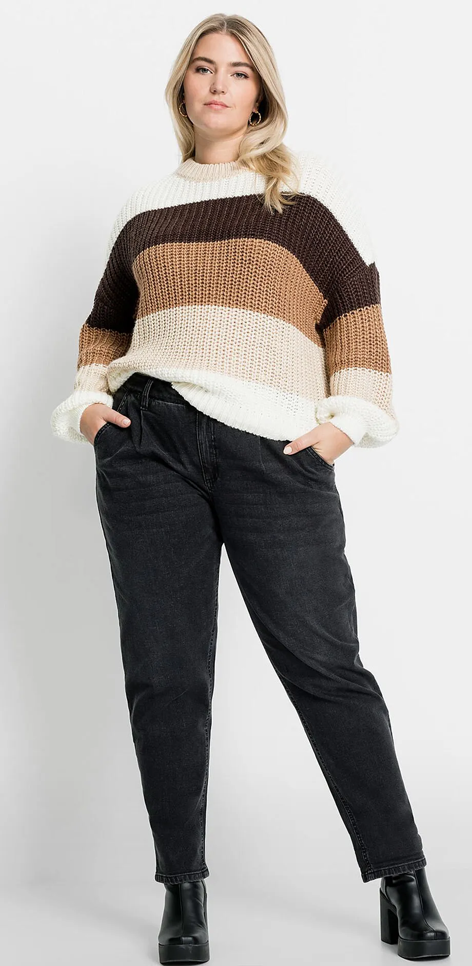 Randig stickad tr&ouml;ja i jordn&auml;ra toner, kombinerad med m&ouml;rka jeans och svarta skor.

