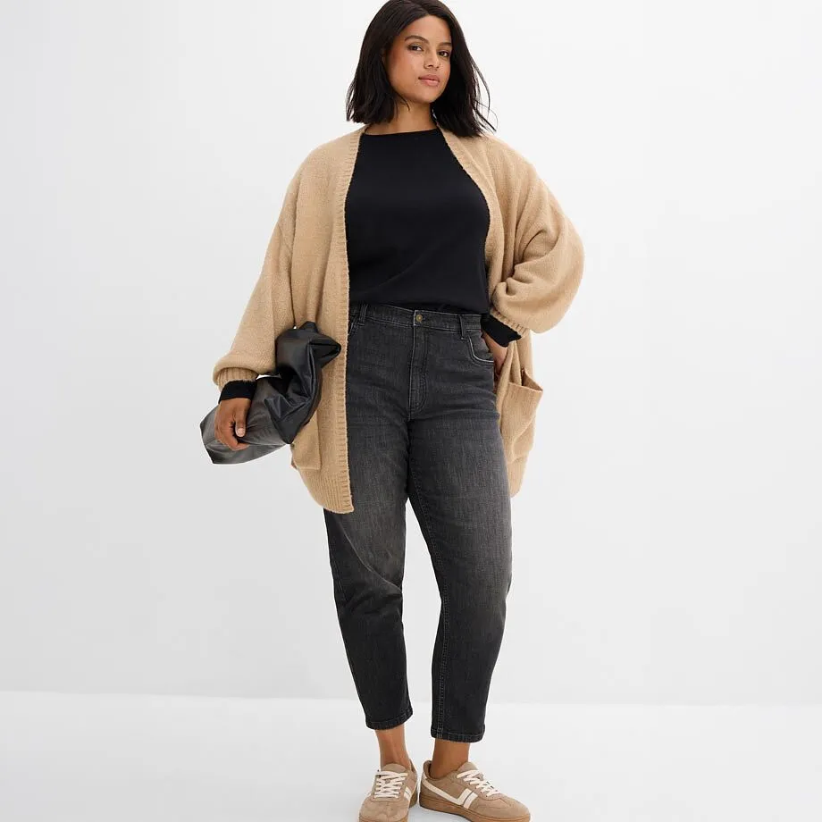 Beige cardigan &ouml;ver en svart &ouml;verdel, till det gr&aring;a jeans och beigea sneakers.