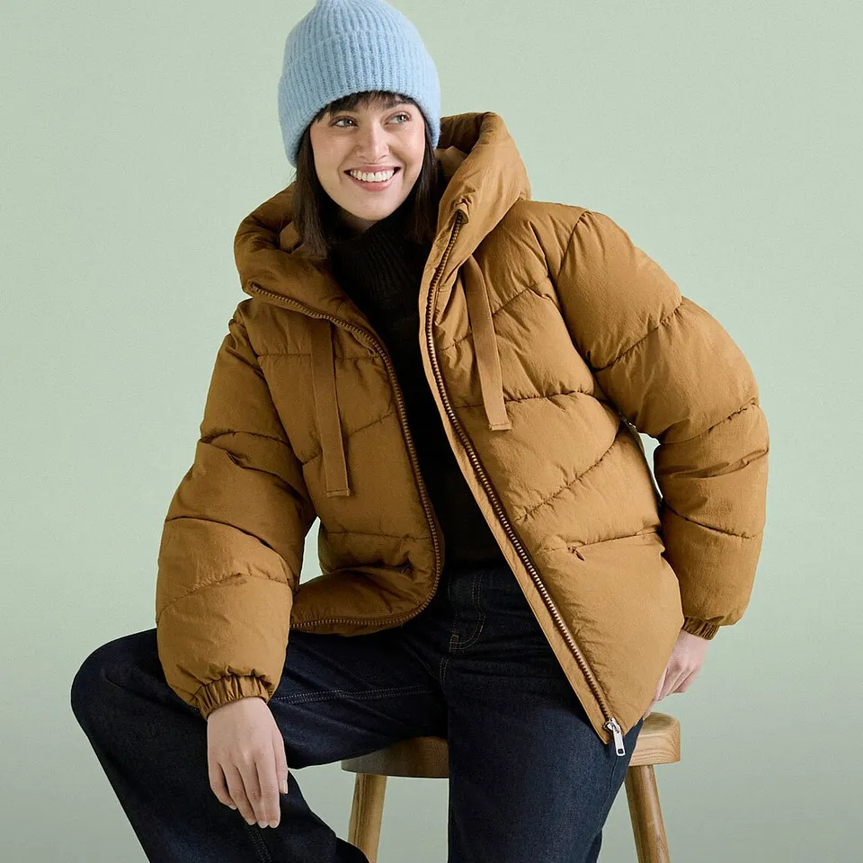 Bl&aring; m&ouml;ssa, brun t&auml;ckjacka och m&ouml;rka jeans.