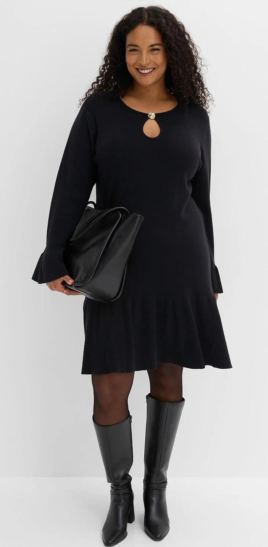 Elegant, svart kl&auml;nning med urringning, till det strumpbyxor, kn&auml;h&ouml;ga st&ouml;vlar och handv&auml;ska.