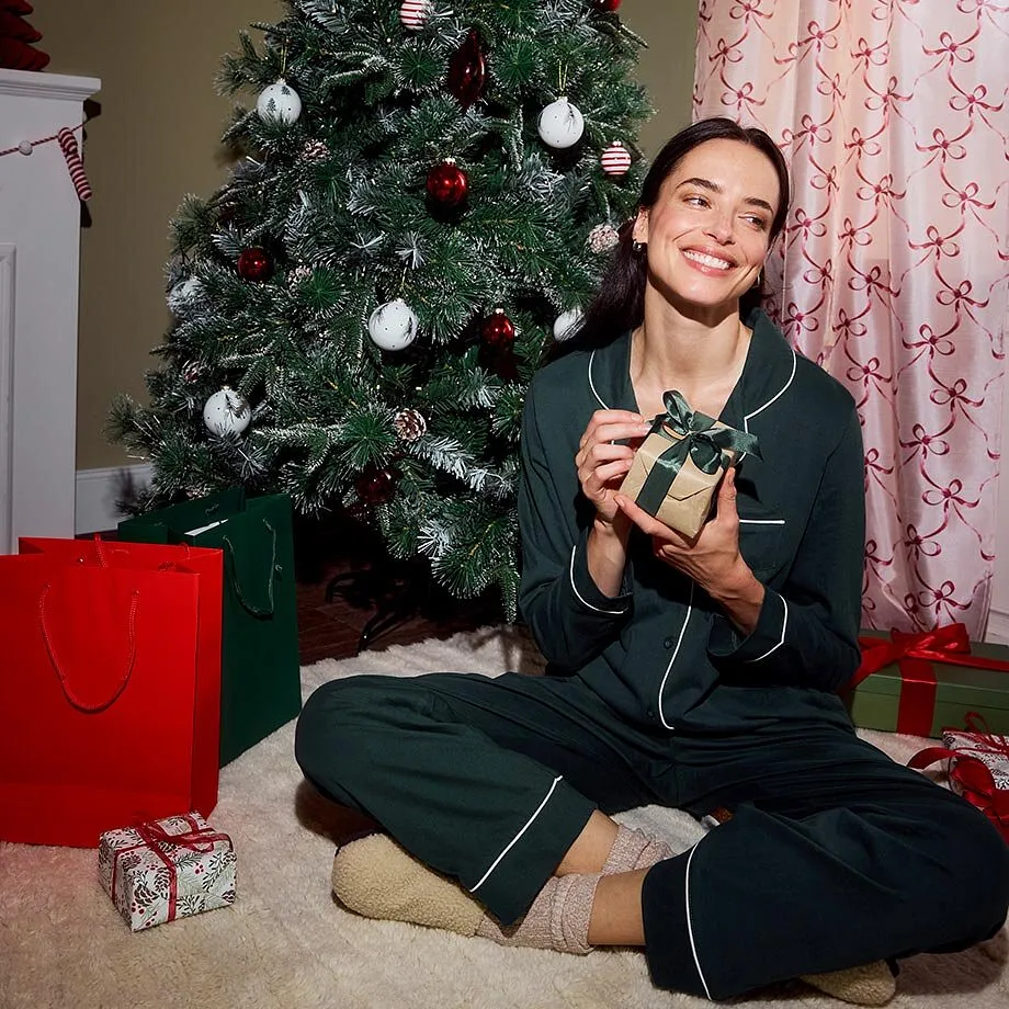Hon sitter framf&ouml;r en kl&auml;dd julgran.