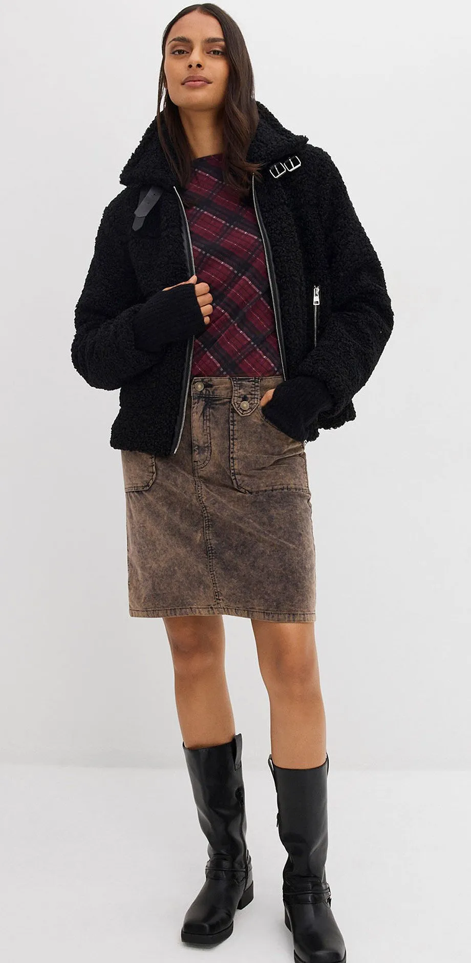 Svart jacka, rutig tr&ouml;ja, brun manchesterkjol och kn&auml;h&ouml;ga st&ouml;vlar.

