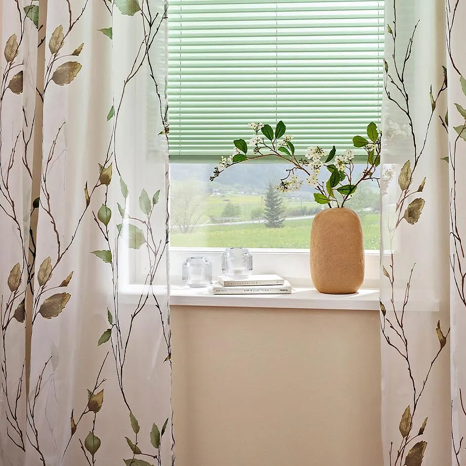 Gardiner med blomm&ouml;nster pryder f&ouml;nstret.