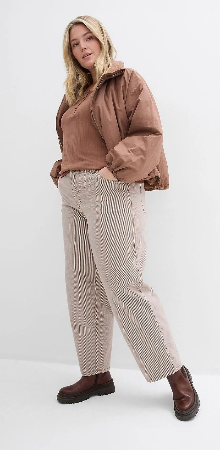 Brun jacka och topp, beiga byxor och m&ouml;rkbruna skor.

