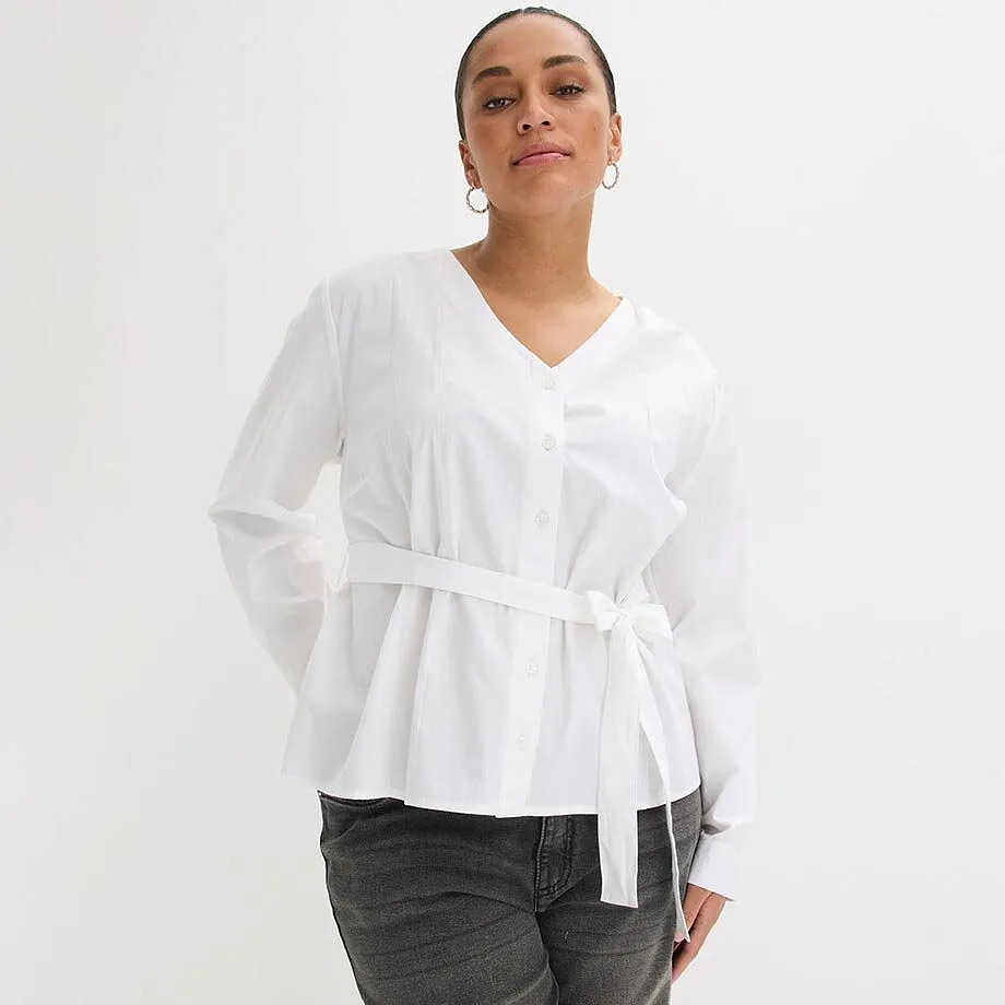 Vit blus med V-ringning och b&auml;lte, kombinerad med m&ouml;rka jeans.

