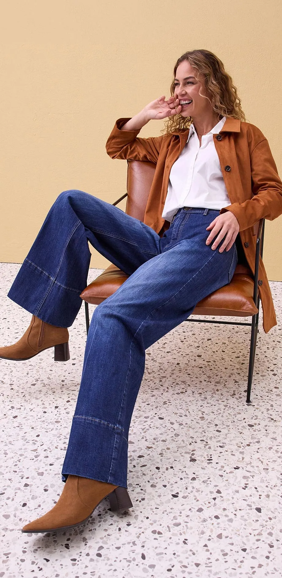 Brun l&auml;derjacka, vit skjorta och vida jeans.

