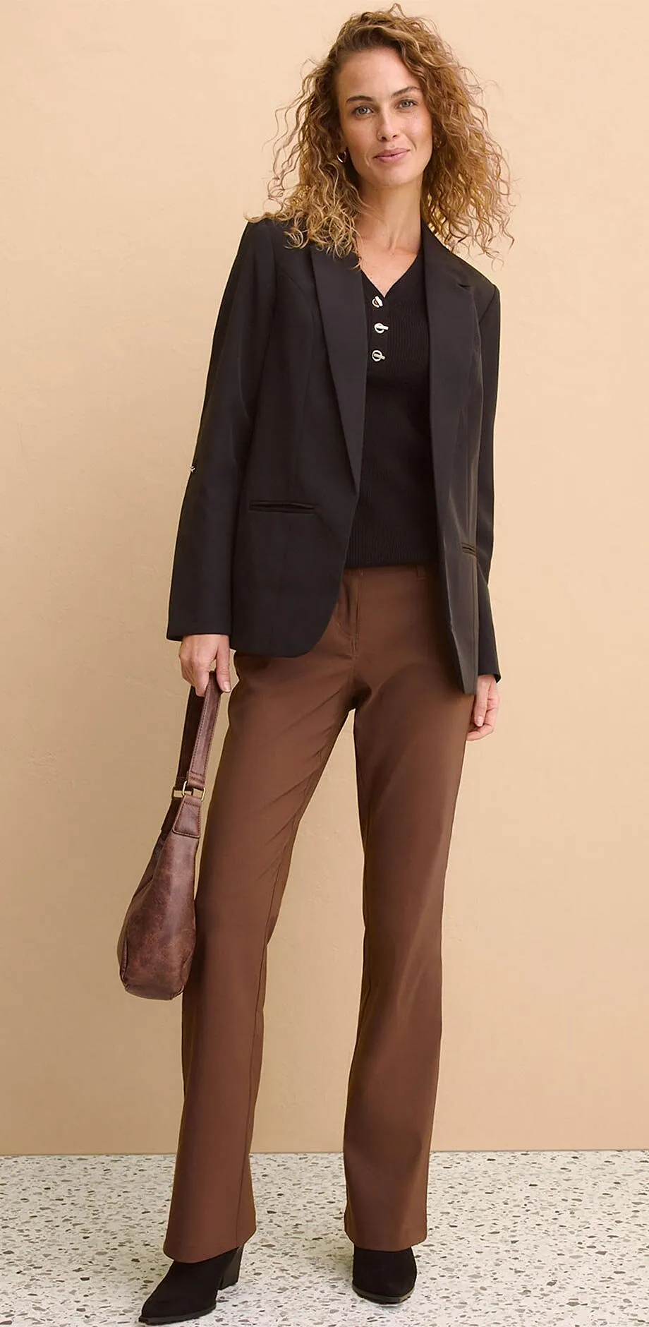 Svart kavaj &ouml;ver m&ouml;rkt linne, kombinerat med bruna byxor.

