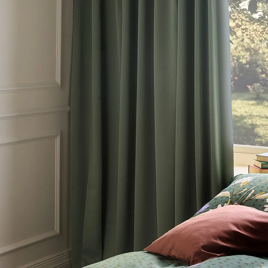 Gr&ouml;na gardiner pryder f&ouml;nstret.

